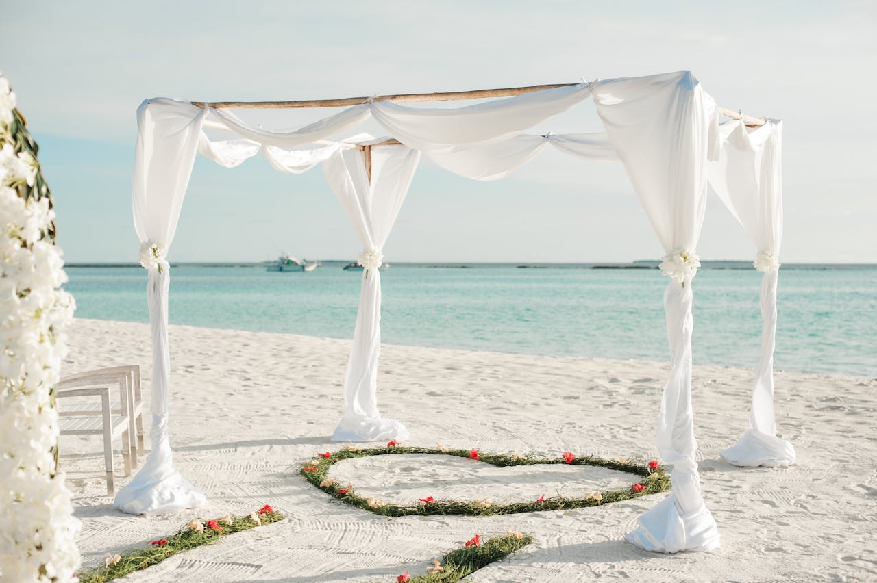 Beautiful beachfront wedding arch with floral decorations on a sunny day in Maldives.